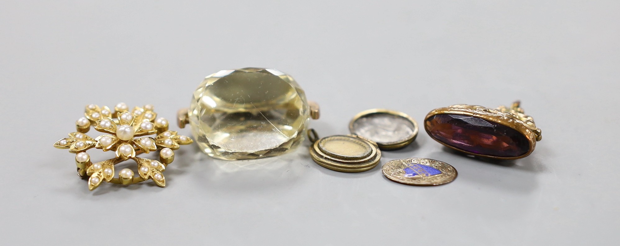 An Edwardian yellow metal and seed pearl cluster set pendant brooch, 27mm, a George V 9ct gold mounted citrine spinning fob, one other gilt metal fob and a damaged locket.